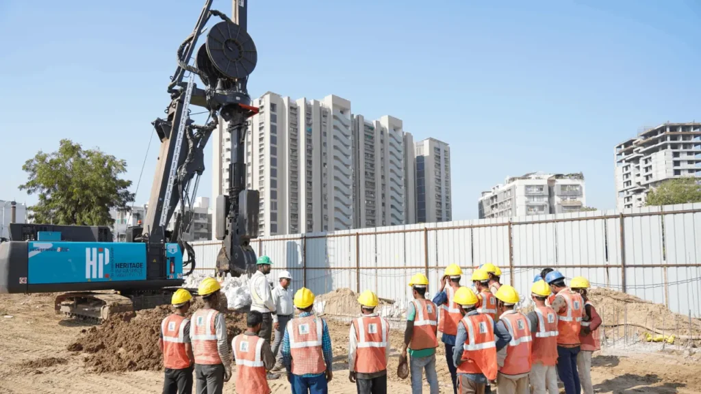 A group of workers stand next to a hydraulic rig for diaphragm wall construction